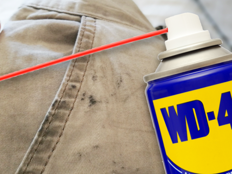 Eine mit Ölflecken verschmutzte Hose und davor eine Dose WD-40.