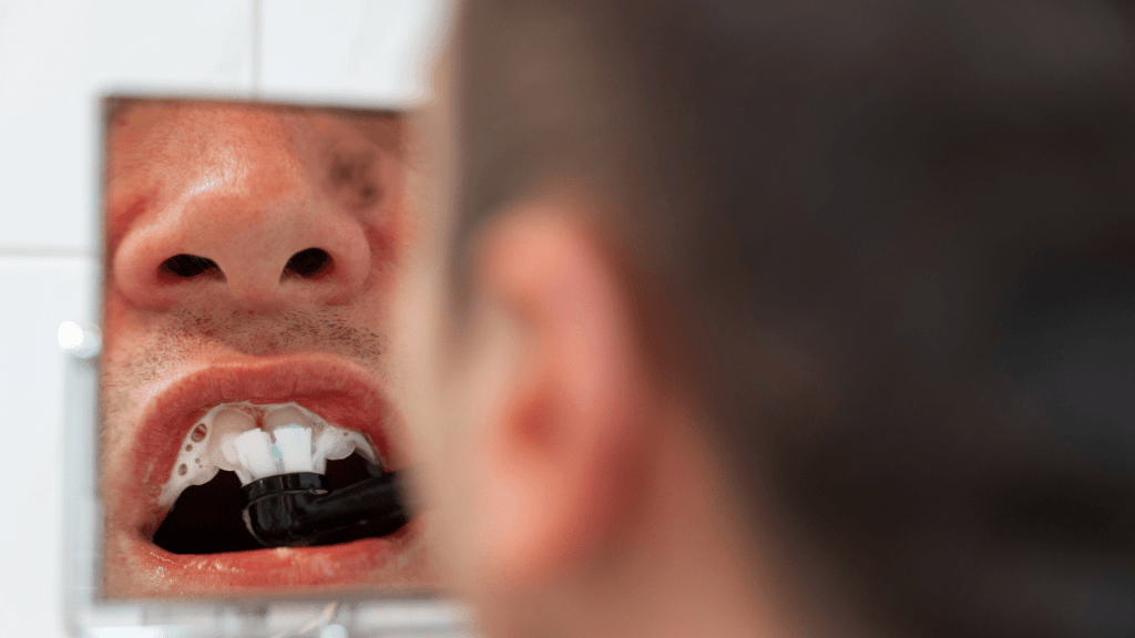 Die Nahaufnahme eines Mannes, der sich seine Zähne putzt.