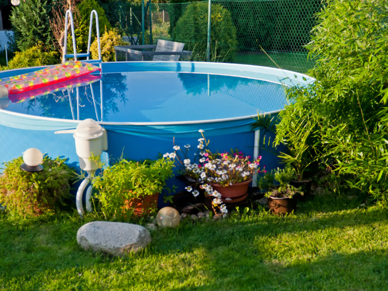 Ein aufgestellter blauer Pool im Garten.