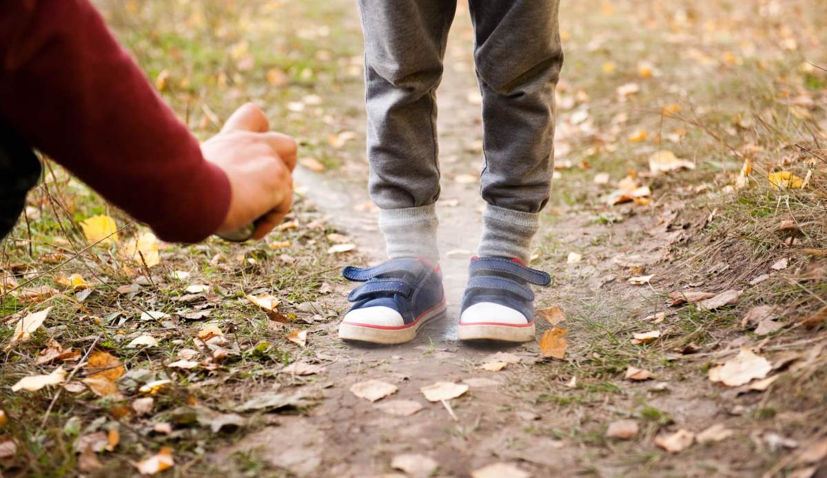 Die Schuhe eines Jungen werden mit Mückenspray eingesprüht.