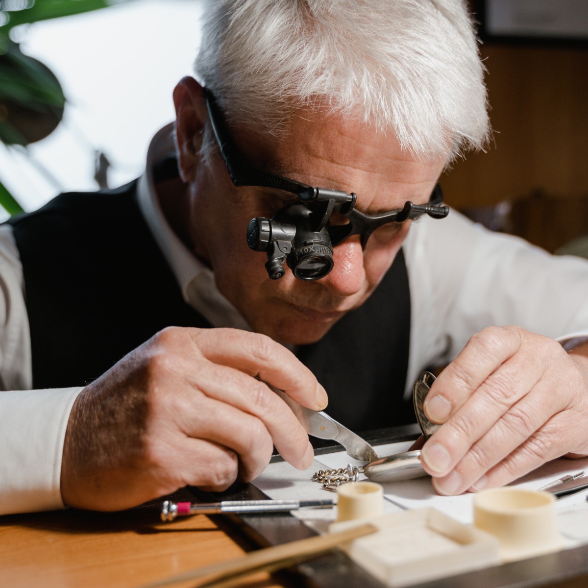 Ein Job ohne Menschen: Ein Uhrmacher repariert mit einer Speziallupe eine alte Taschenuhr.