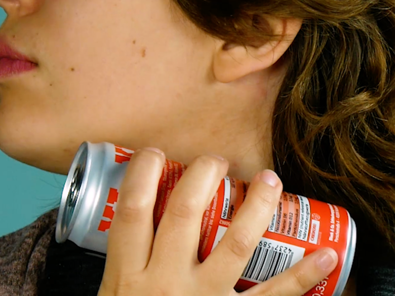 Eine Frau hält sich eine Getränkedose an den Hals.