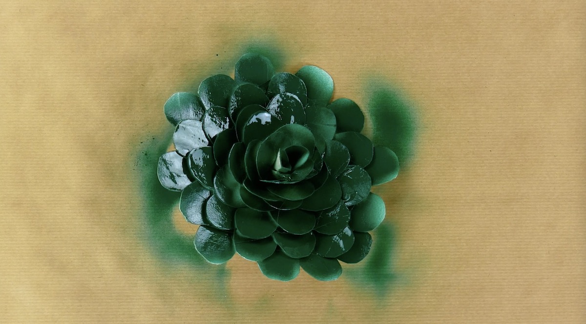 Klebe die Tropfen zu einer Blüte zusammen und besprühe diese mit grüner Farbe