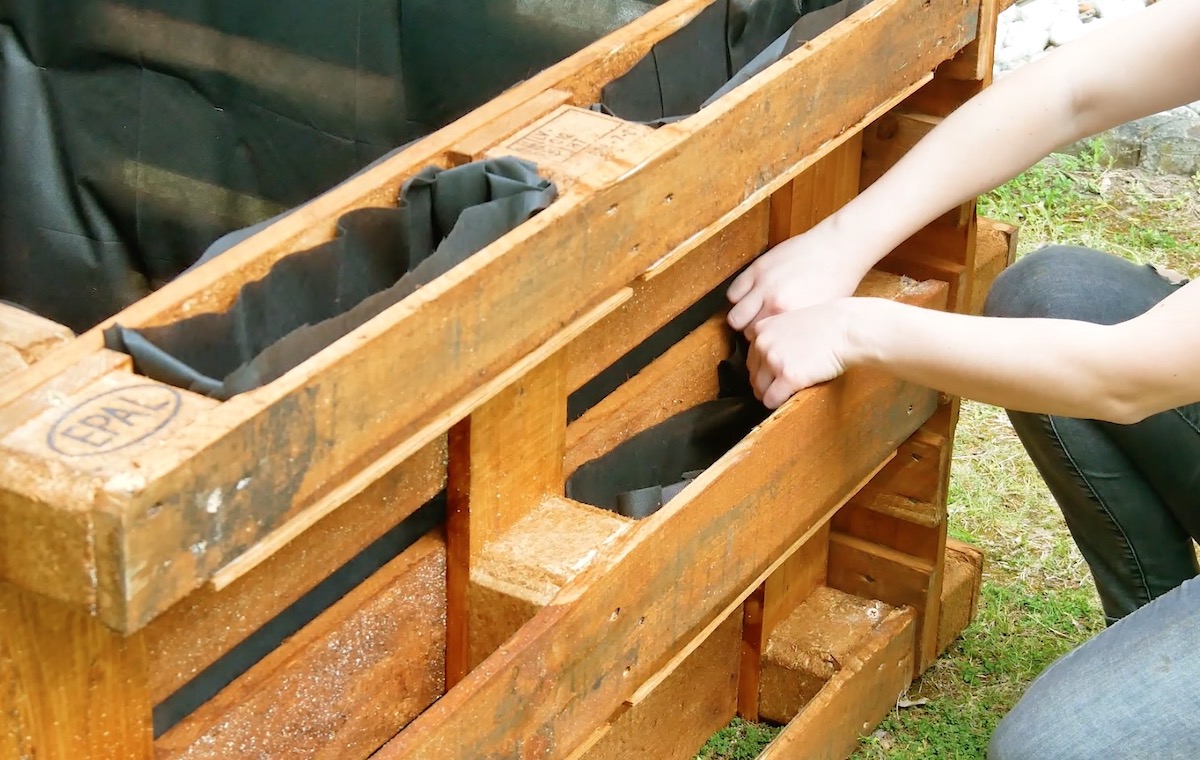 Die Zwischenräume der Paletten werden mit schwarzem Vlies ausgekleidet.