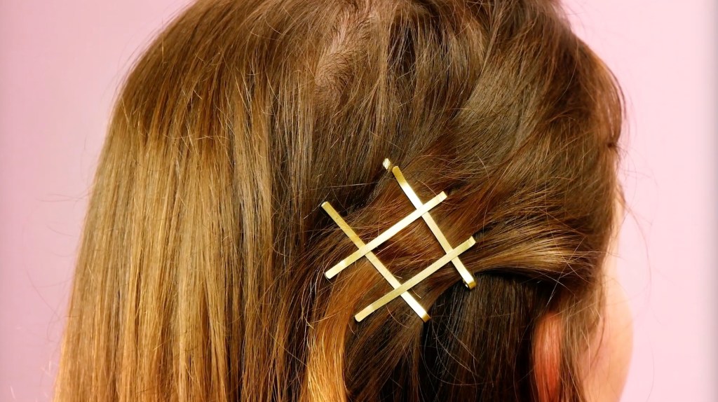 Goldene Haarklammern zu einer Raute ins Haar gesteckt.