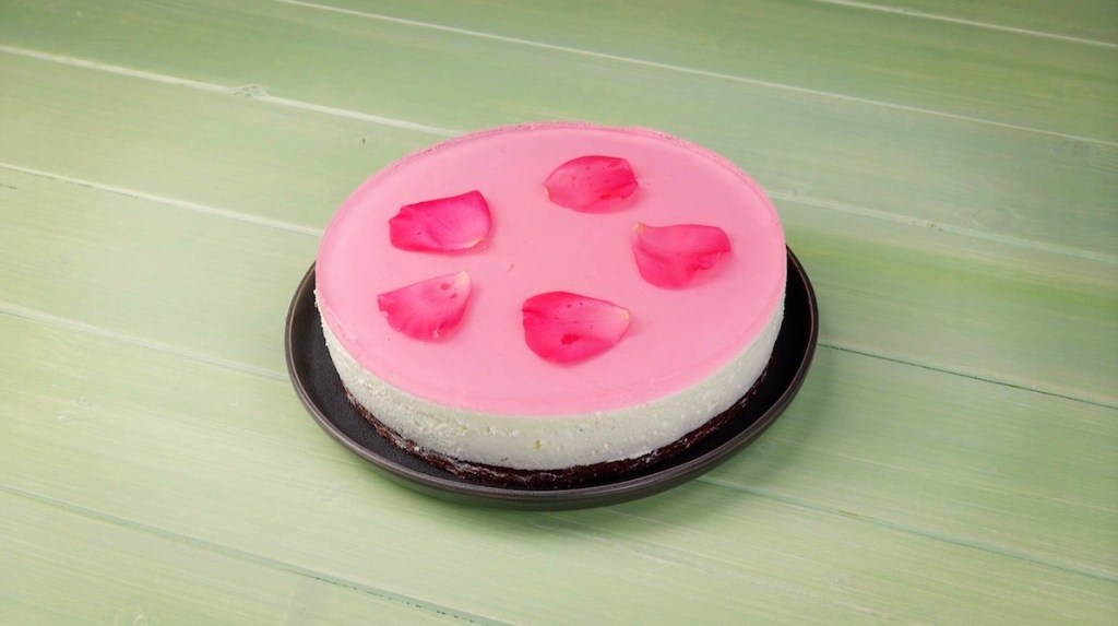 Eine Torte mit rotem Tortenguss und Blüten.
