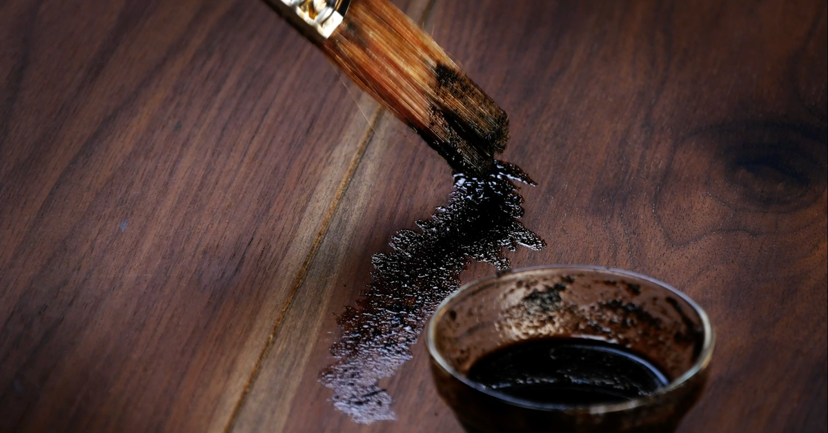 Kaffeesatz wird mit einem Pinsel auf Holz aufgetragen