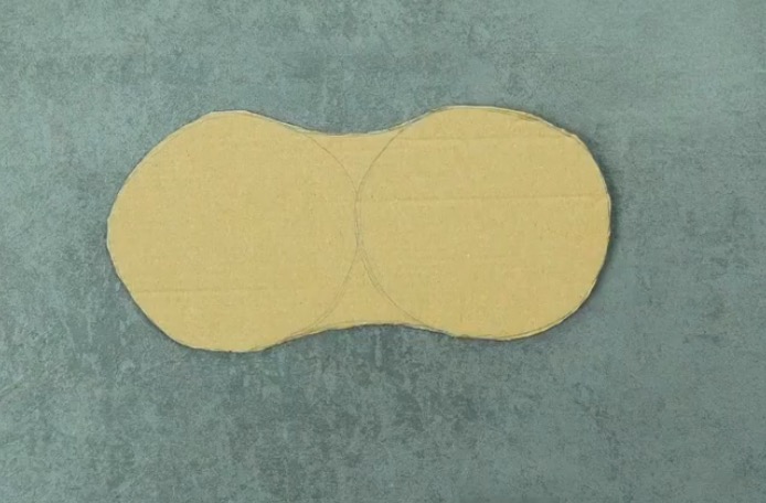 Eine Sohlenform wird aus einem Stück Pappe geschnitten. 