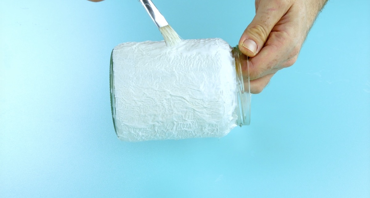Beklebe ein Einmachglas mit Klopapierstückchen.