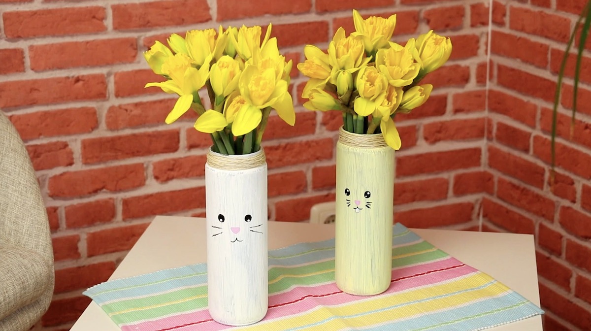 Zwei Vasen mit Gesicht, in denen Osterglocken stehen.