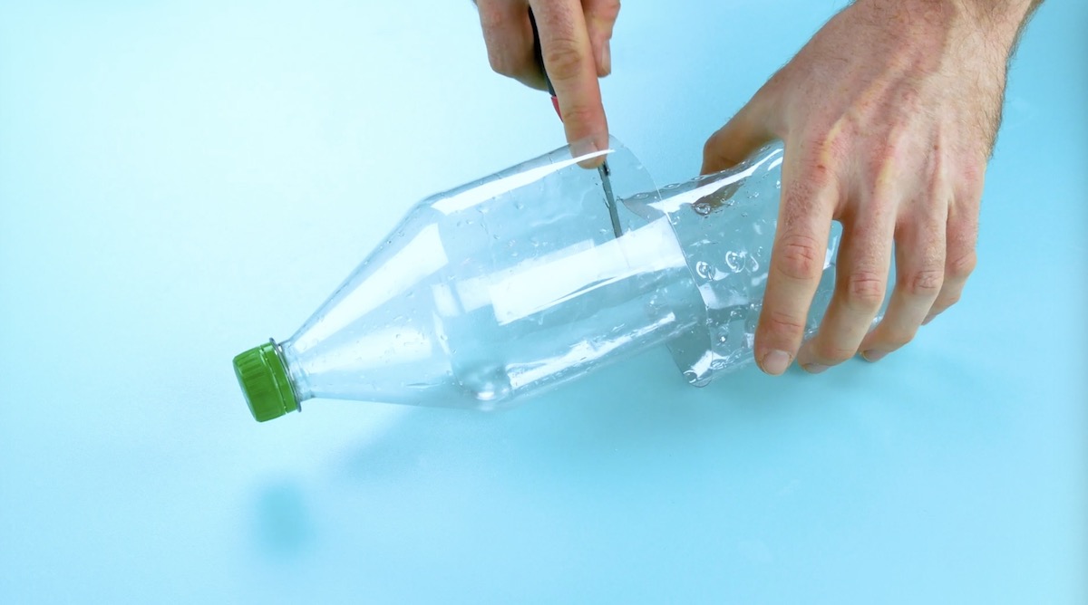 Jemand halbiert eine Plastikflasche