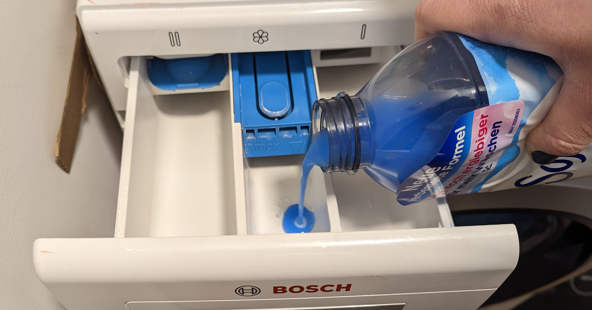 Blauer WeichspÃ¼ler wird in die Waschmittelkammer einer Waschmaschine gefÃ¼llt.
