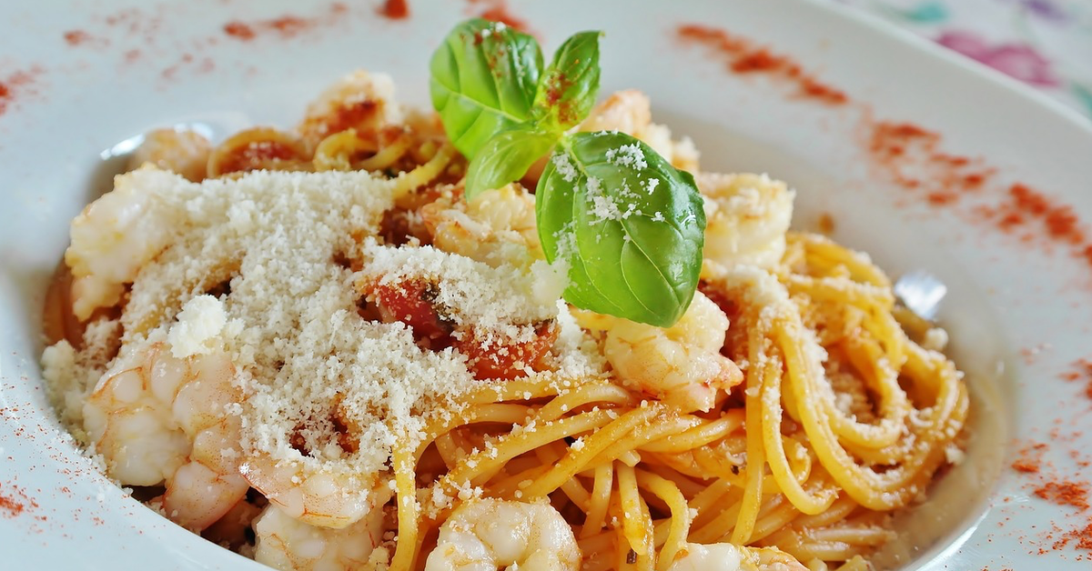 Ein voller Teller Spaghetti mit Parmesan und ein paar Basilikum-Blättern