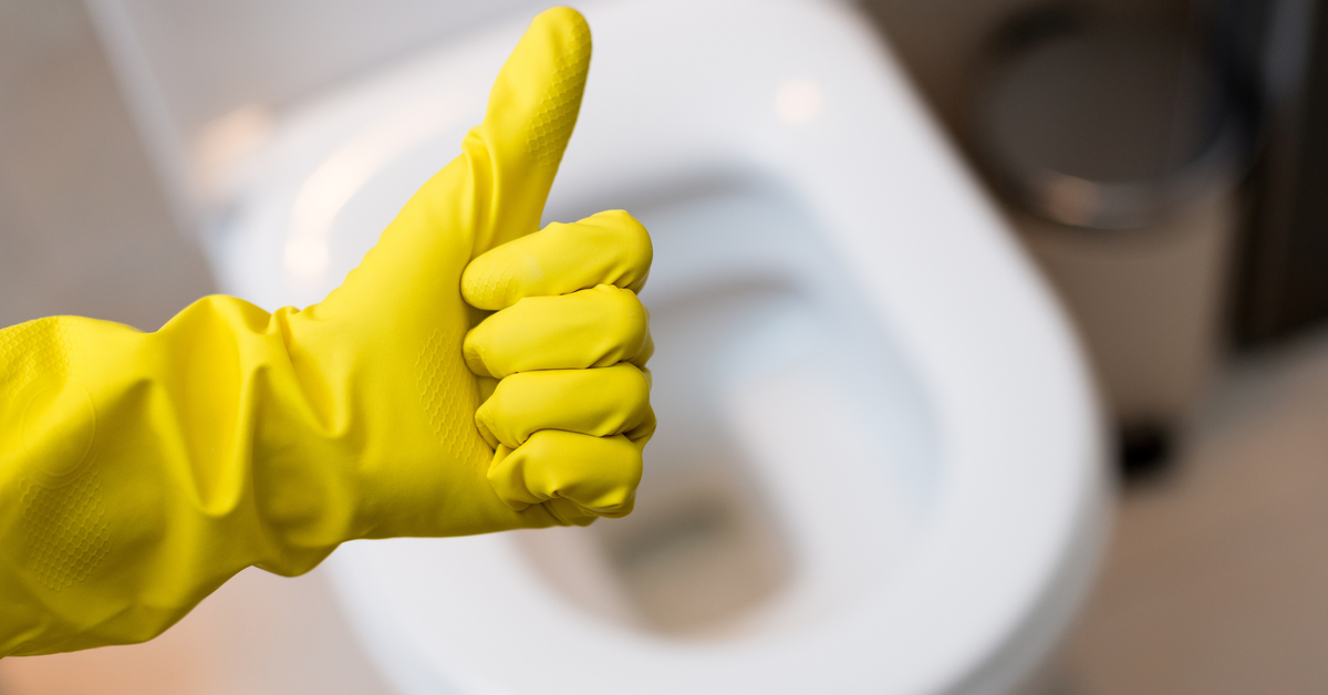 Gelber Gummihandschuh mit "Daumen-hoch-Geste" vor einer ToilettenschÃ¼ssel