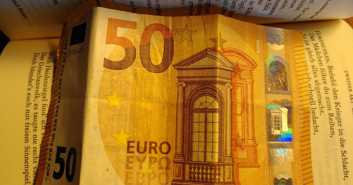 Eine FÃ¼nfzig-Euro-Note liegt auf einem aufgeklappten Buch.