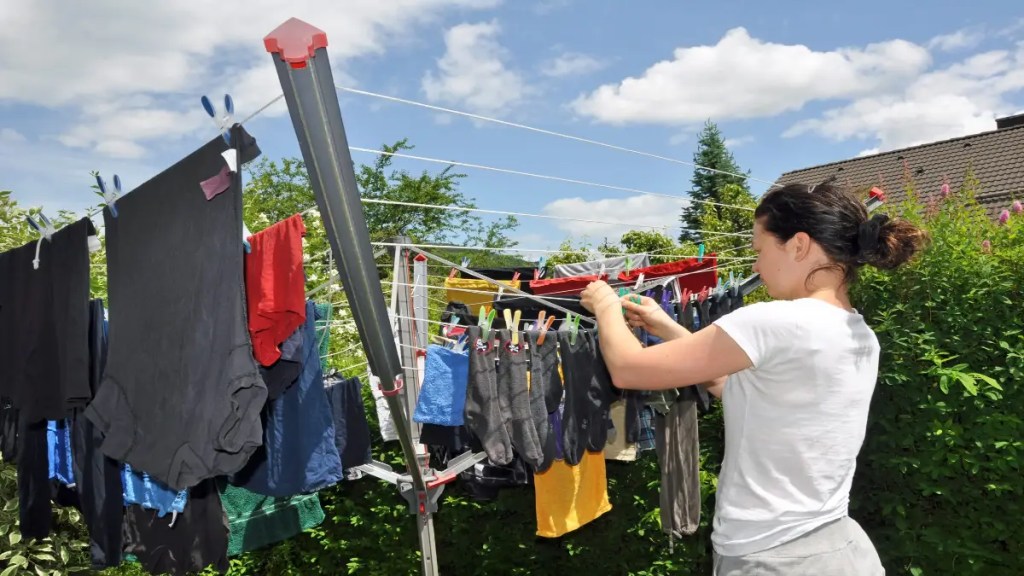 Eine Frau hängt Kleidung auf eine Wäscheleine.