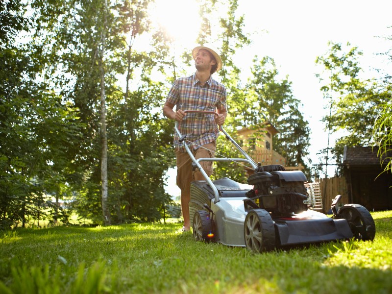 Mann mäht Rasen im Garten