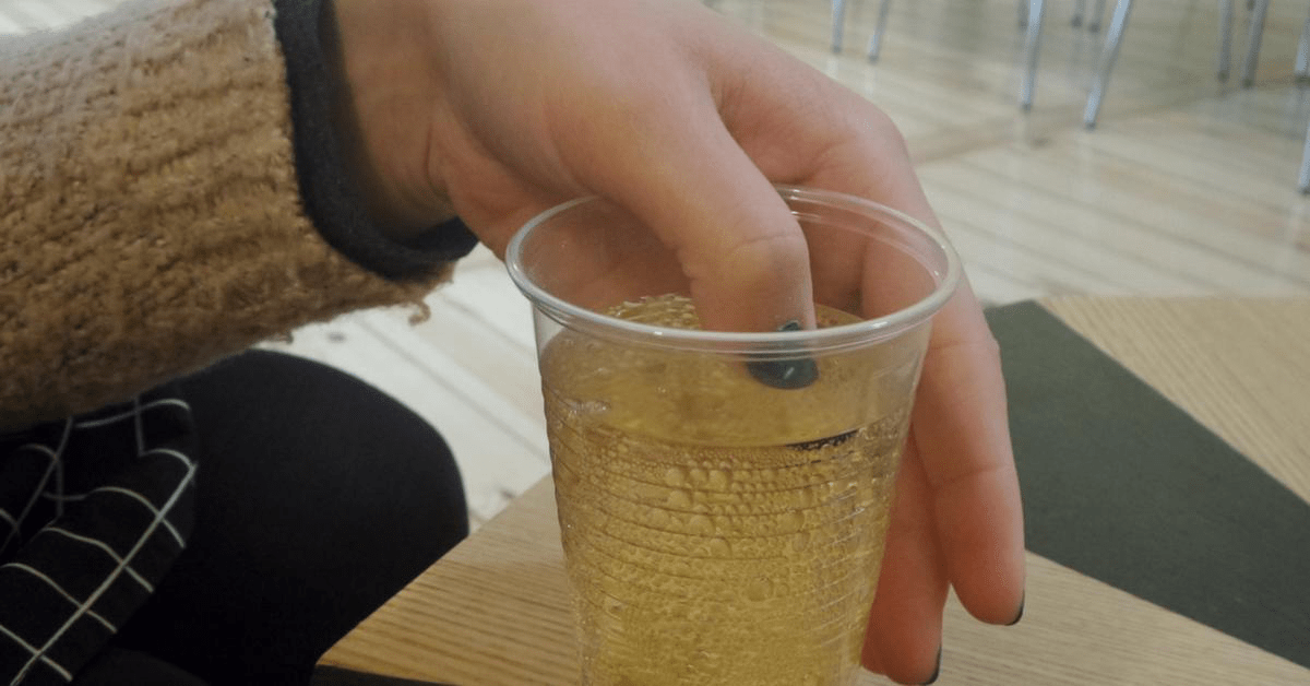 Eine Frau hält einen lackierten Fingernagel in ein alkoholisches Getränk. Kann man mithilfe eines Nagellacks K.-o.-Tropfen erkennen?