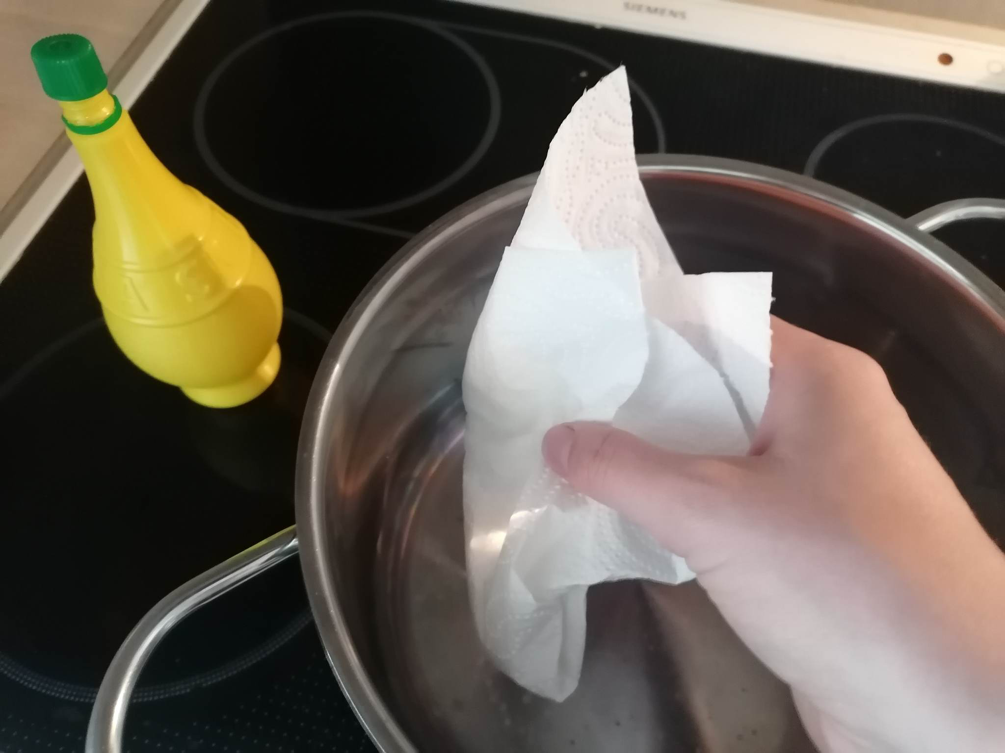 Topfboden reinigen: Jemand wischt einen Topf mit Zitronensaft aus, um Verfärbungen zu entfernen.