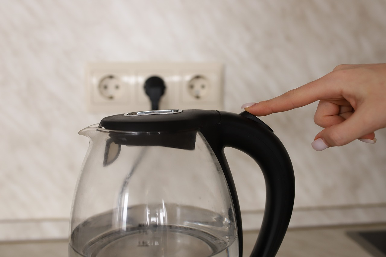 Eine Person schaltet einen Wasserkocher an. Hierbei ist es wichtig, dass die MindestfÃ¼llmenge nicht ignoriert wird.