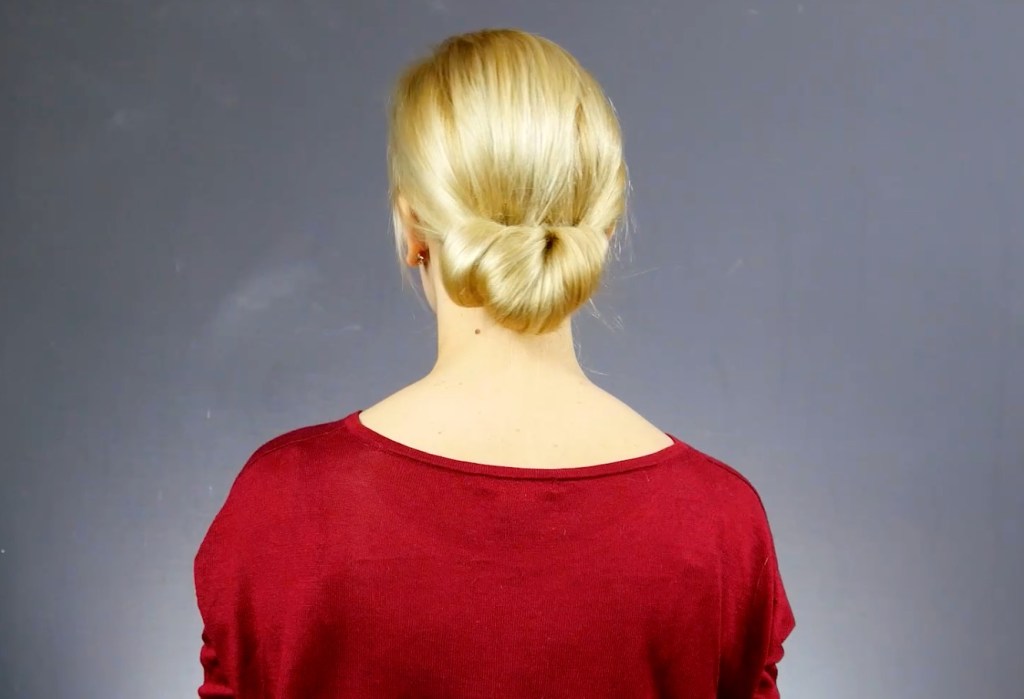 Von hinten fotografiert: Eine blonde Frau mit Hochsteckfrisur.