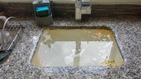 Ein schmutziges Waschbecken in einer Küche wird mit Wasser befüllt.