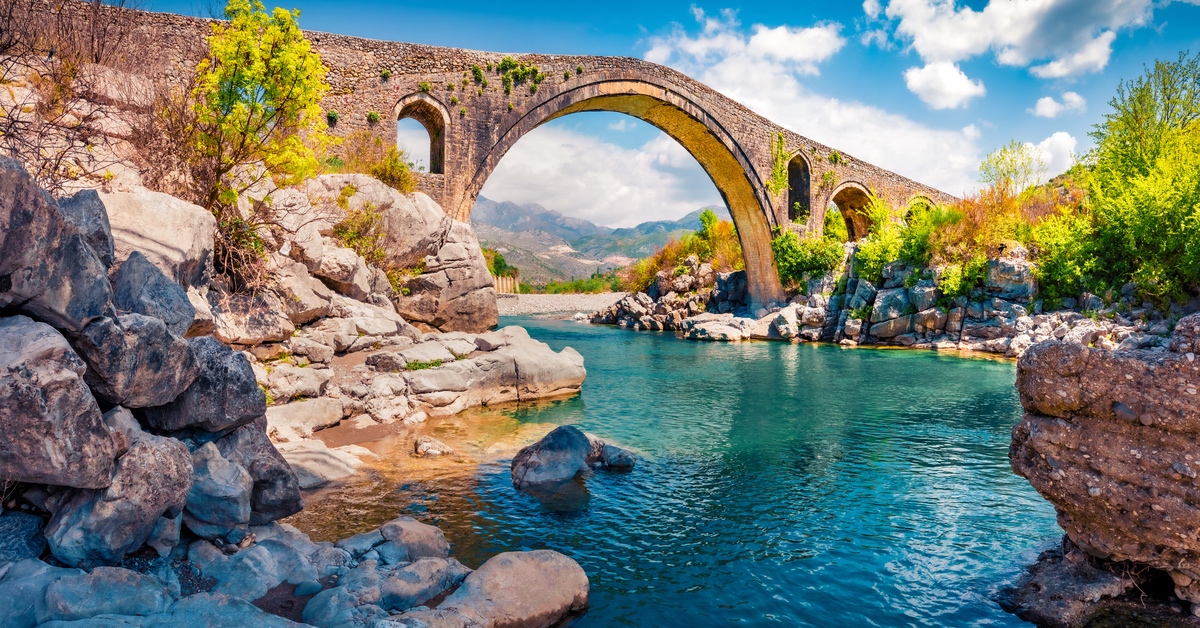 Eine SteinbrÃ¼cke Ã¼ber ein grÃ¼n-blaues GewÃ¤sser