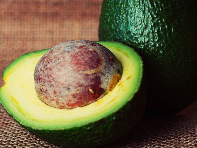 Eine aufgeschnittene Avocado mit einem großen Kern. Avocadokern verwenden.