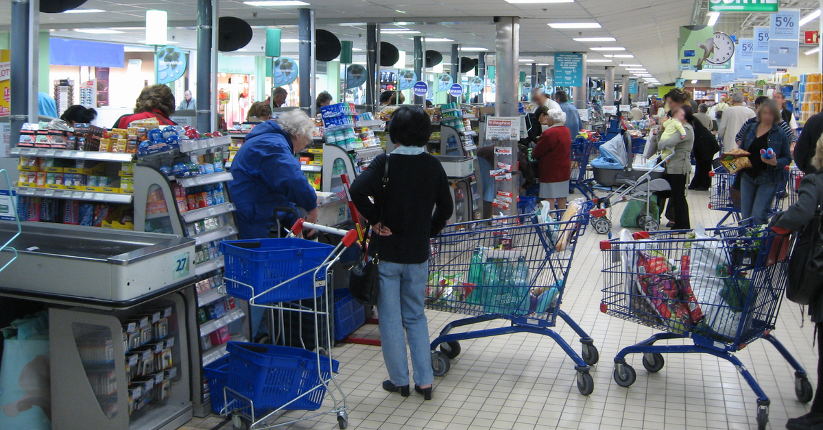 Kassenbereich eines Supermarkts, viele Menschen stehen an den zahlreichen Kassen.