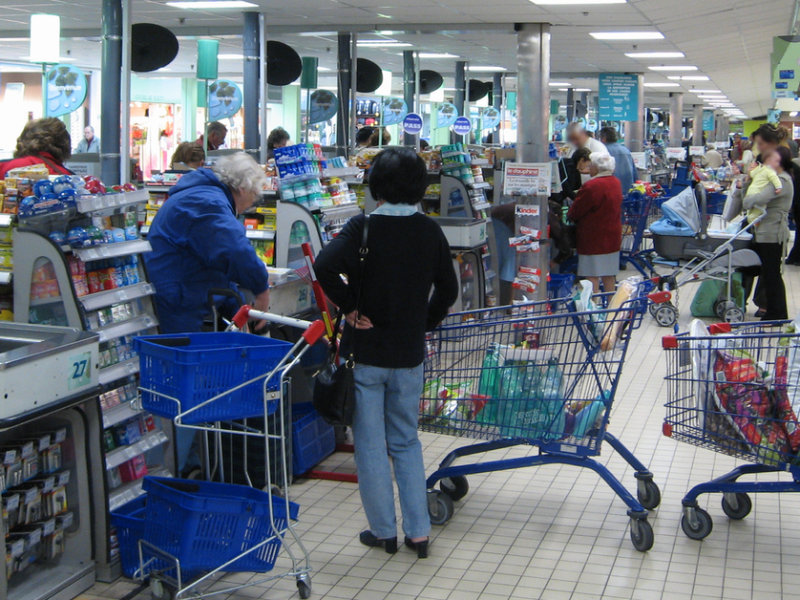 Kassenbereich eines Supermarkts, viele Menschen stehen an den zahlreichen Kassen.