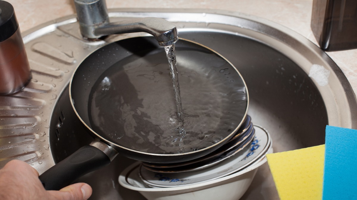eine beschichtete Pfanne wird mit klarem Wasser ausgespült