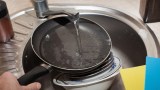eine beschichtete Pfanne wird mit klarem Wasser ausgespült