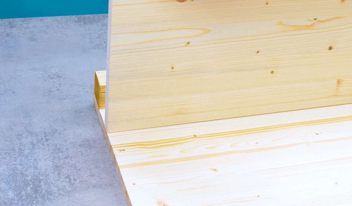 Eine Holzplatte wird im 90-Grad-Winkel auf die Tischplatte gestellt.