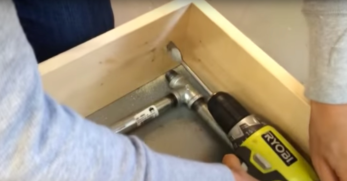 Ein Loch wird mit einer Bohrmaschine in ein Brett gefräst.
