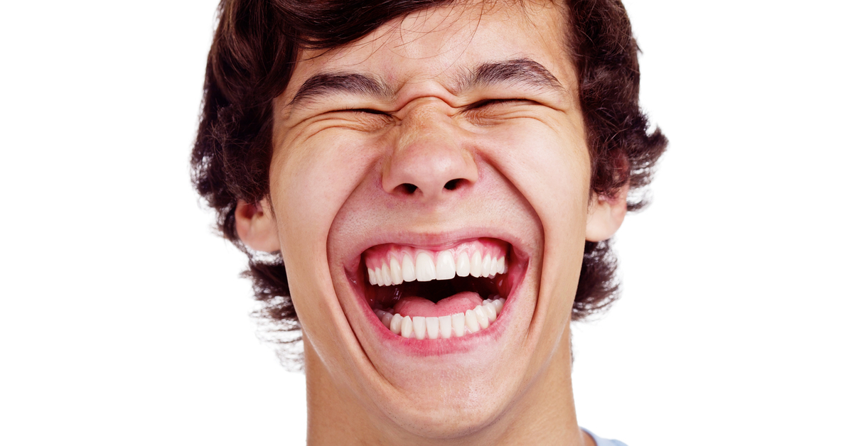 Ein braunhaariger Mann lacht breit in die Kamera, dabei sind seine Augen geschlossen.