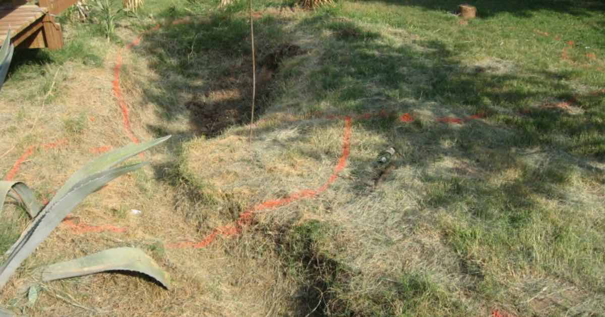 Garten mit überwachsenen Mulden. Markierungen mit roter Farbe kündigen schon das nächste DIY-Projekt an.