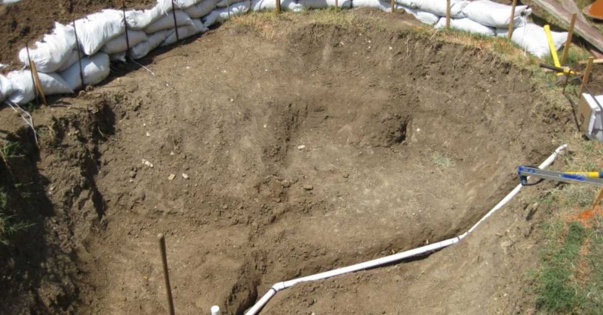 Große Grube für einen Pool, der angelegt ist wie ein Gartenteich.
