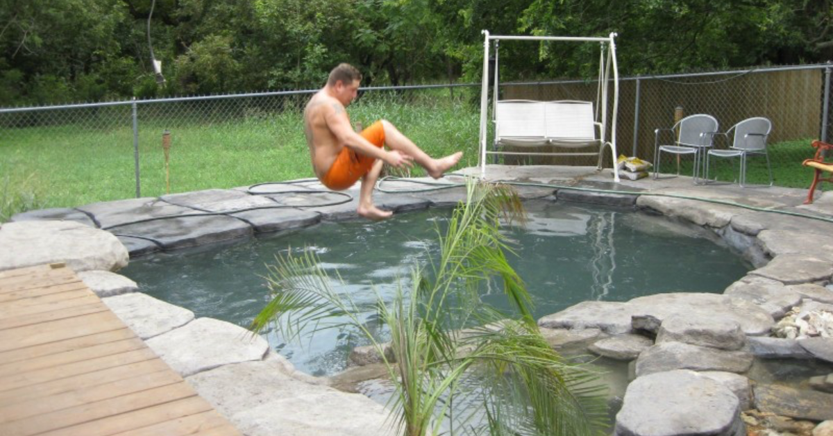 Mann springt in den mit Wasser gefüllten Gartenteich.