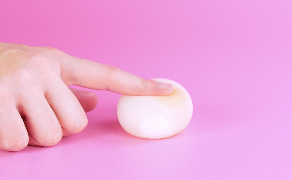 Ein Finger drückt ein weiches Ei ein.
