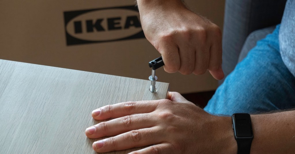 Ein Mann dreht eine Schraube in ein IKEA-Möbelstück.