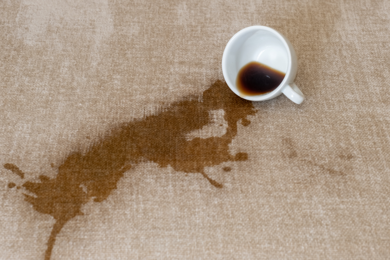 kaffeefleck entfernen Eine Tasse Kaffee ist auf weichem Untergrund ausgekippt. Mit einem simplen Putztrick kannst du den Fleck entfernen.
