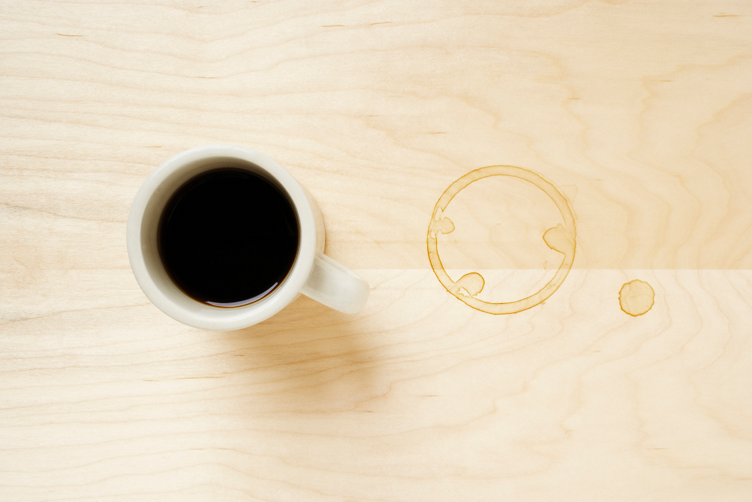 Eine Kaffeetasse und rechts daneben ein Fleck, der durch die Tasse verursacht wurde. Die KaffeerÃ¤nder lassen sich mit dem KriechÃ¶l WD-40 ganz leicht entfernen.