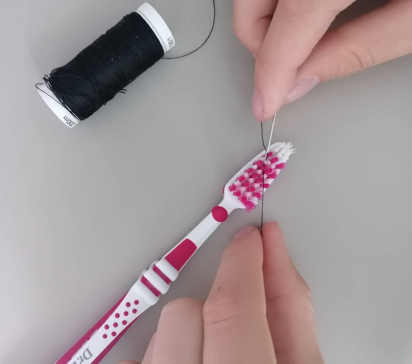 Haushaltstrick, um den Faden mit einer Zahnbürste in das Nadelöhr einzufädeln