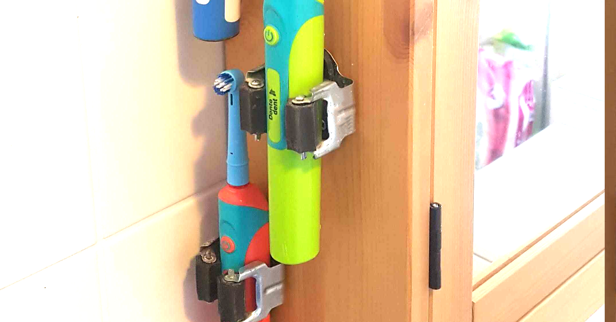 Elektrische ZahnbÃ¼rsten hÃ¤ngen in Besenhalterungen am Badezimmerschrank.