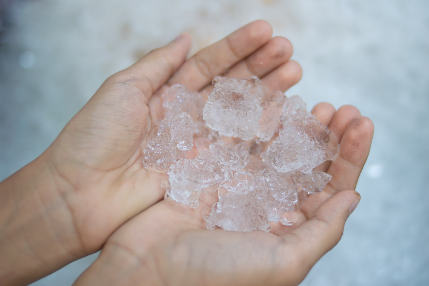 putztricks eis und kälte Eine Person hält einige unregelmäßig geformte Eiswürfel in ihren Händen.