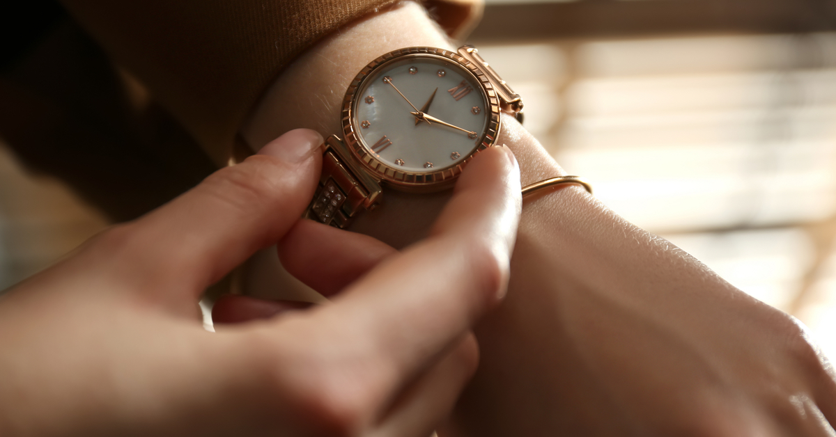 Eine Person schaut auf ihre Armbanduhr am linken Handgelenk.