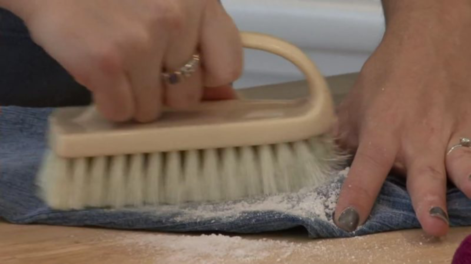 wd-40 flecken entfernen Jemand bearbeitet mit einer Bürste einen Fleck auf einer Jeans. Das Kriechöl WD-40 kann dabei helfen, Fettflecken aus der Kleidung zu entfernen.