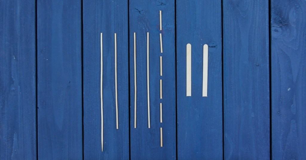 Zahnstocher und Eisstiele zum Basteln sind auf einem blauen Tisch angeordnet.