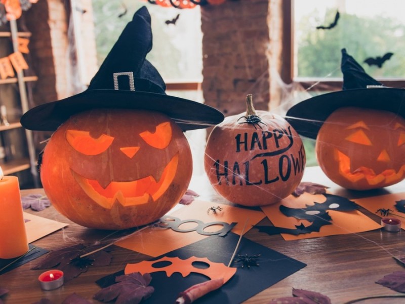 Kürbisse und weitere Halloween-Deko auf einem Tisch.