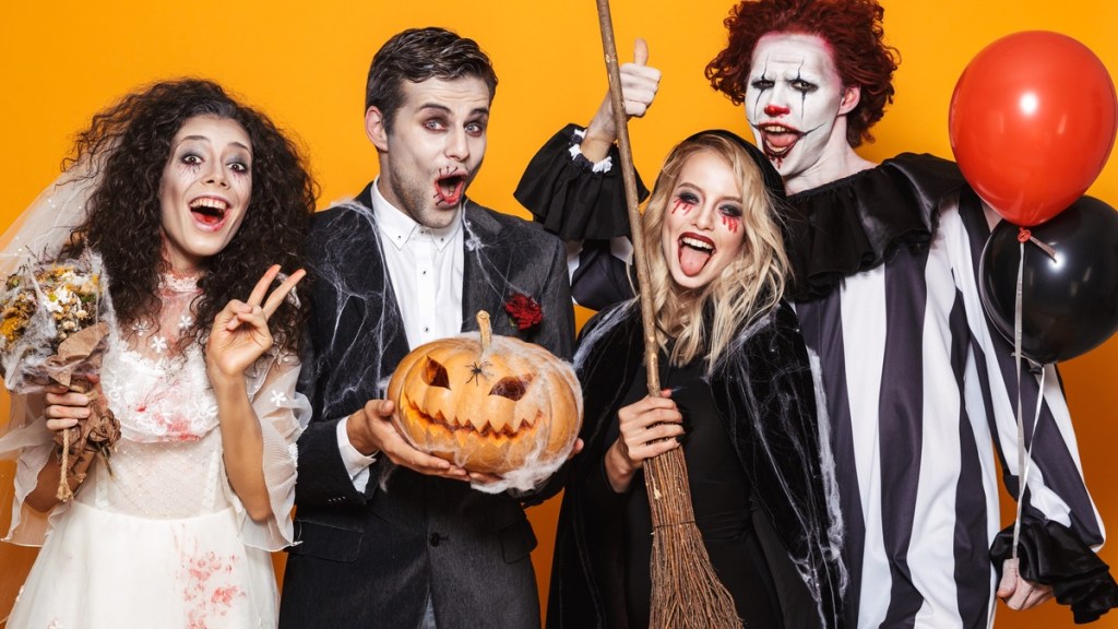 Vier Personen in Halloweenkostümen lachen.